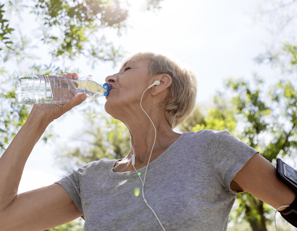 woman drinking water and getting rehydrated after jog