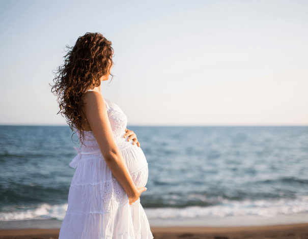 Femme enceinte de dos sur la plage