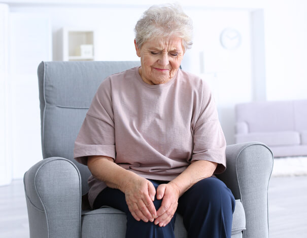 Elderly woman holding her knee because of pain