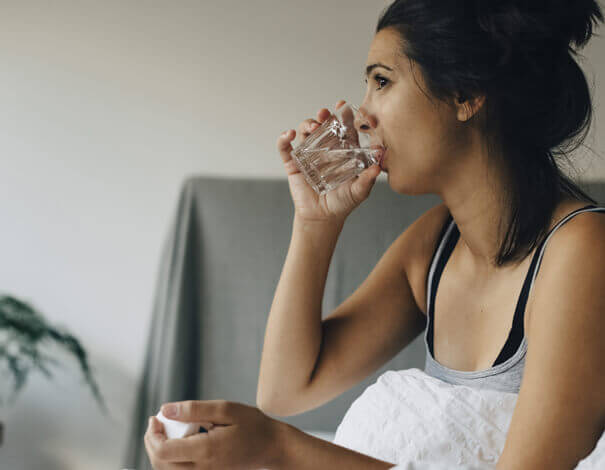 Young Woman taking pill and drinking water