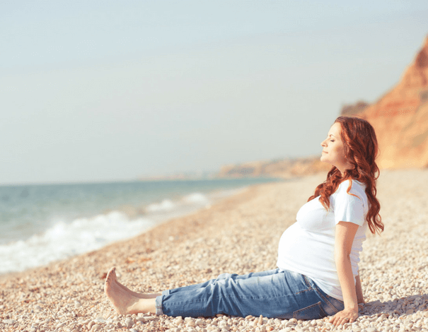 Pregnant woman sitting on the beach