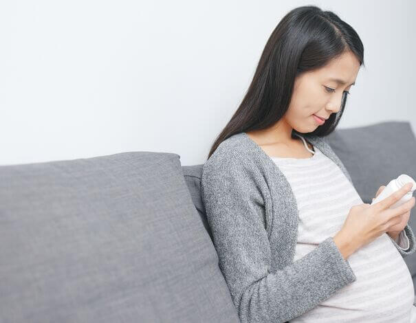 pregnant woman reading pill bottle